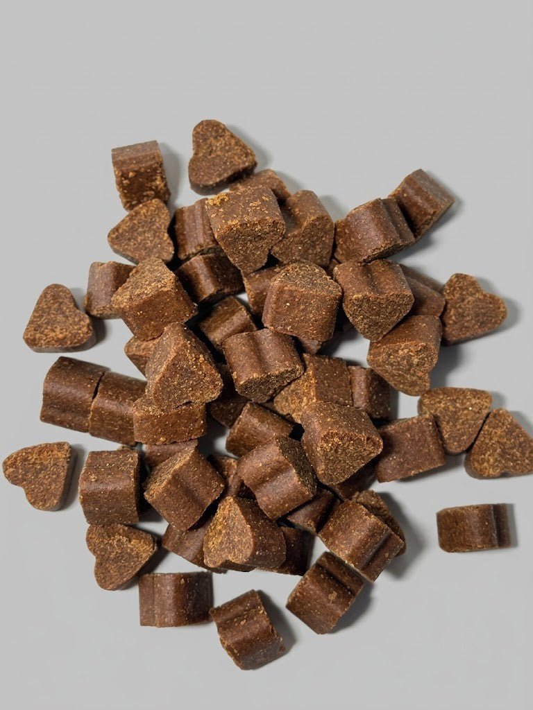 Open container of Hip & Joint soft chews with brown chewable tablets on a gray background