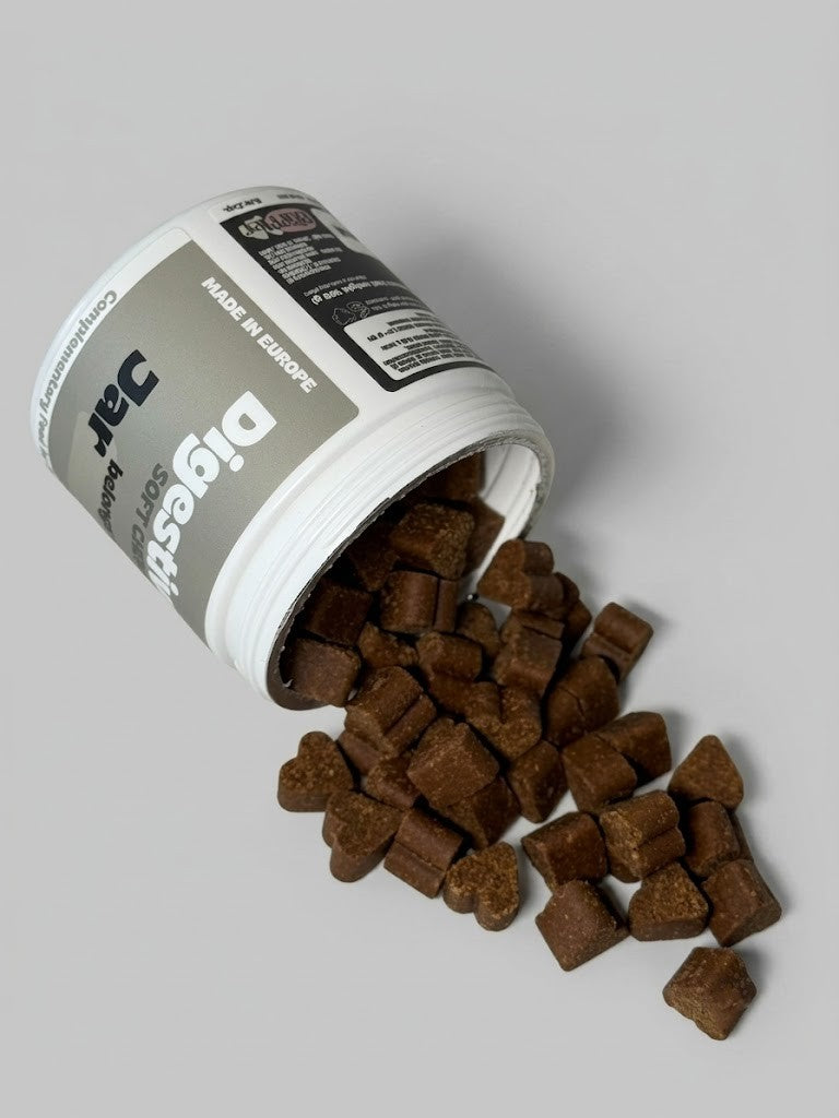 Open container of dog treats spilling out onto a gray surface