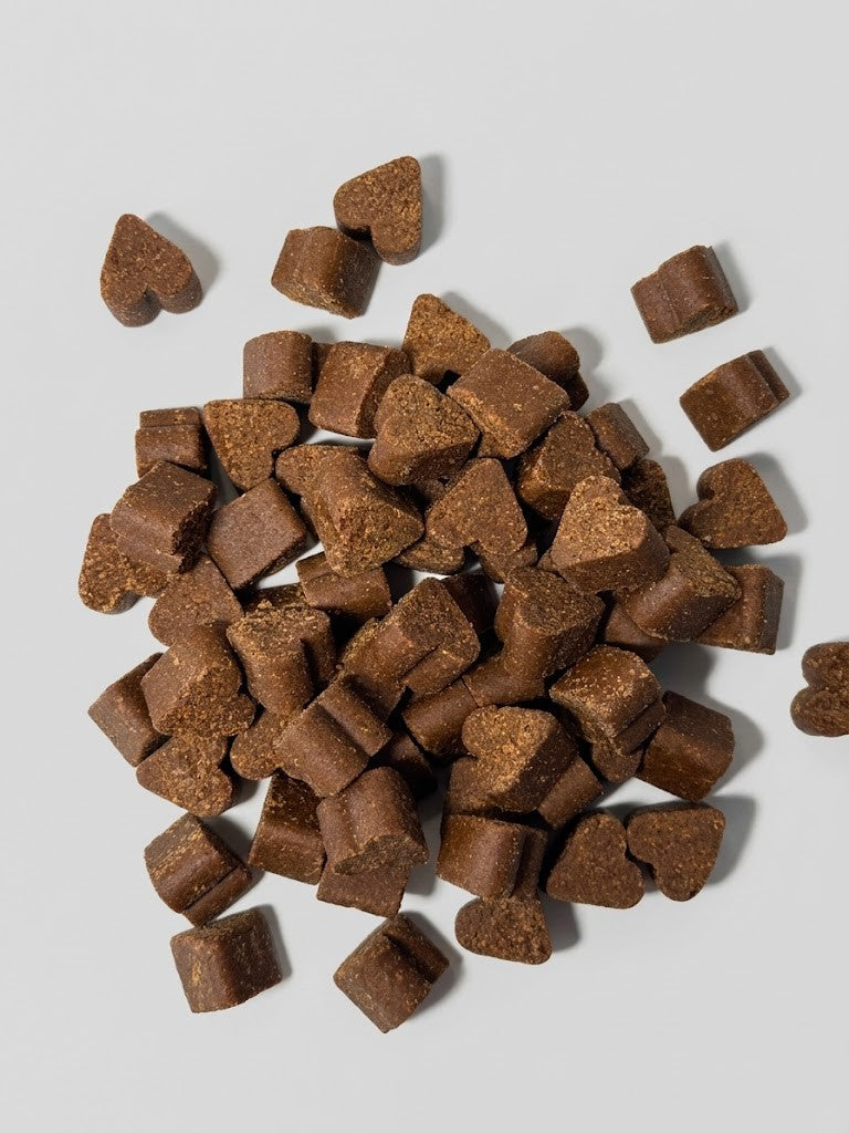 Heart-shaped brown dog treats on a light gray background